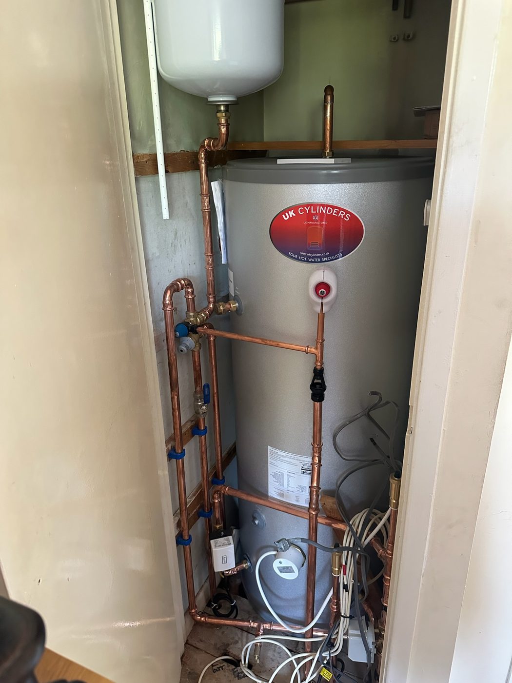 Hot water cylinder with copper pipework and expansion vessel in a cupboard