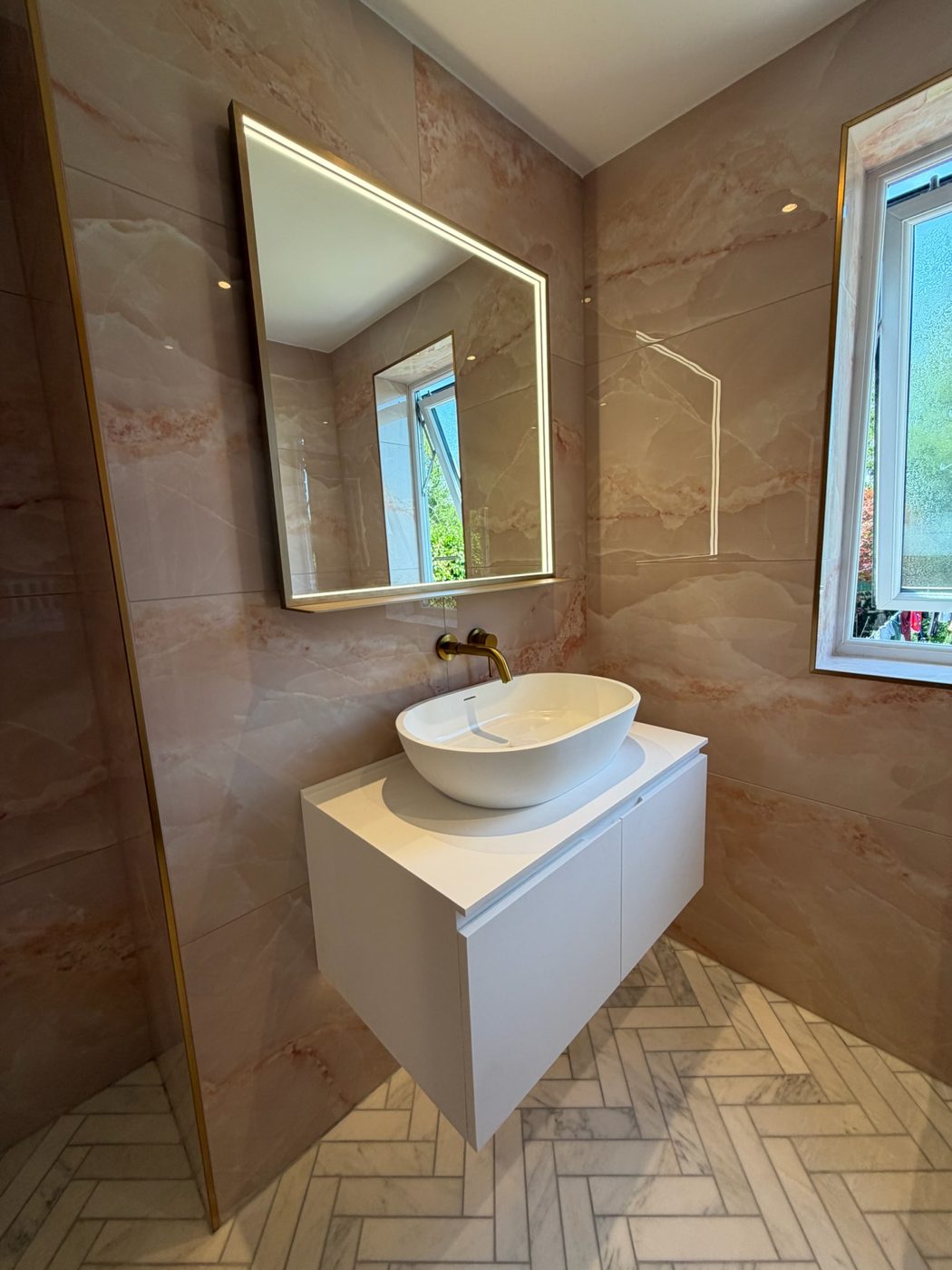 Counter top basin on a wall hung vanity unit with a backlit mirror