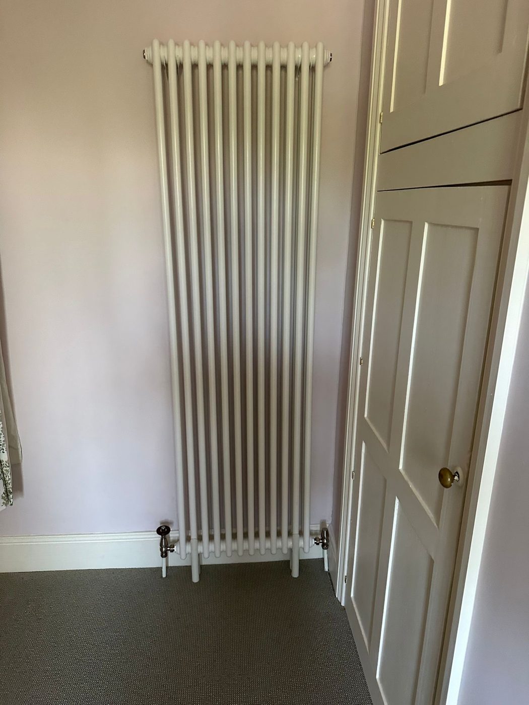 Tall white column radiator fitted in a hallway