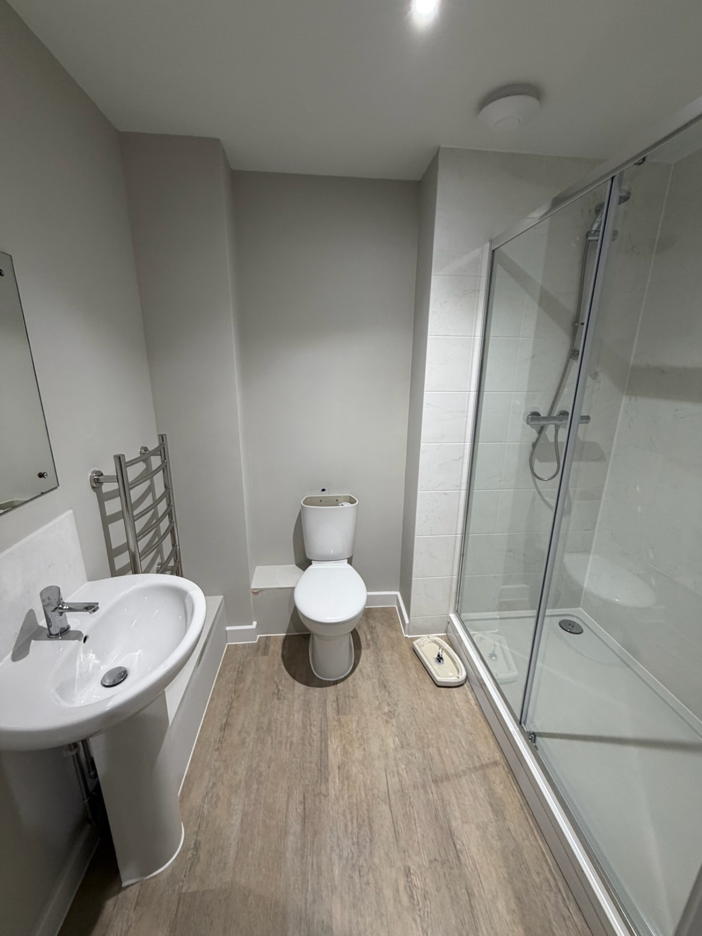 Finished shower room with basin, toilet, heated towel rail and sliding glass shower enclosure