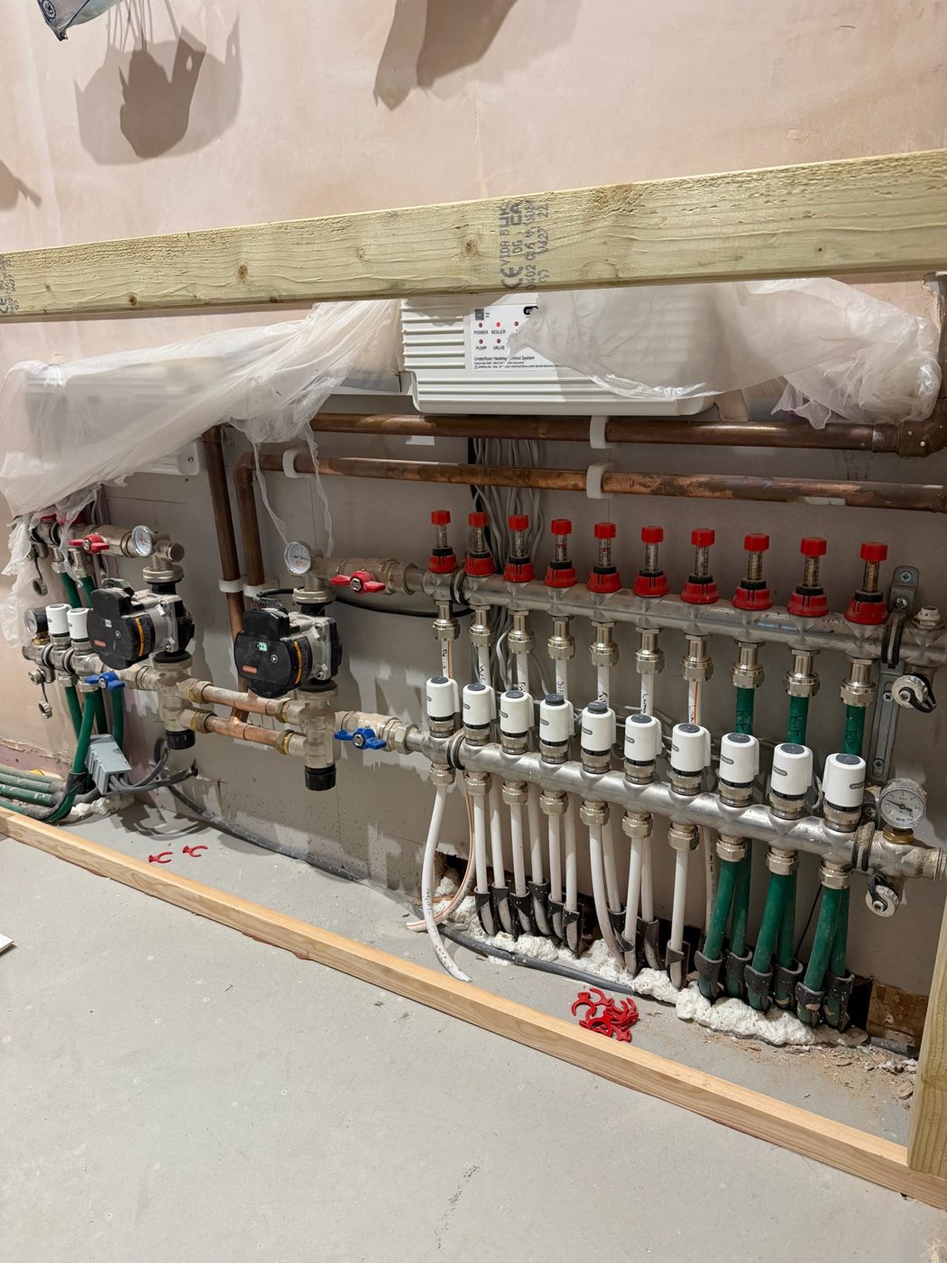 Underfloor heating manifold with actuators and flow meters mounted on a wall