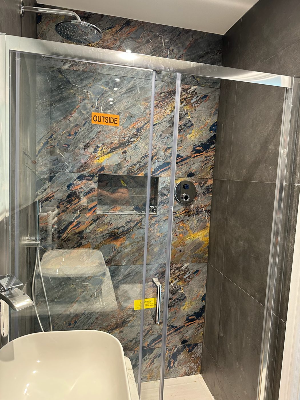 Shower room with patterned stone effect tiling and a glass shower enclosure
