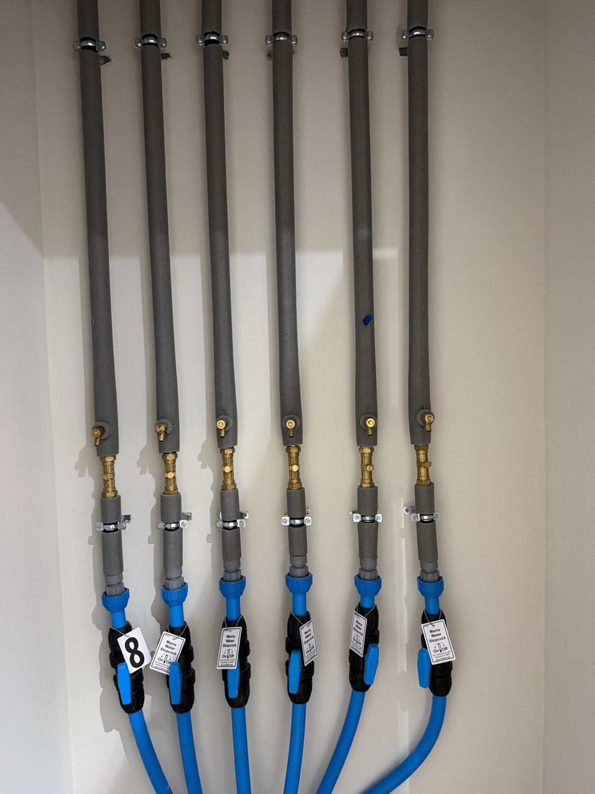 Insulated water main risers with brass fittings feeding six apartments from MDPE supplies