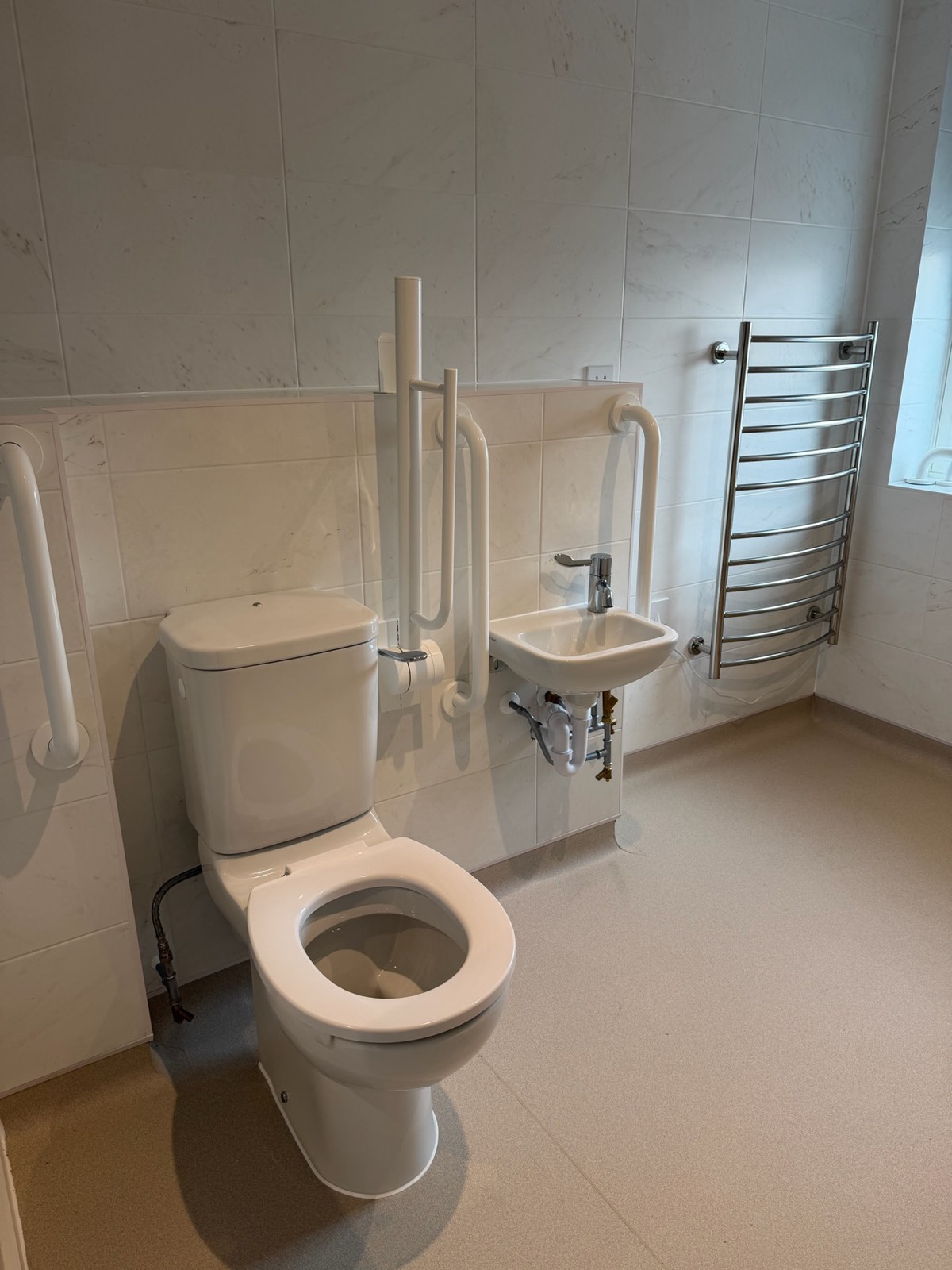 Completed accessible wet room with grab rails, low-level WC and heated towel rail