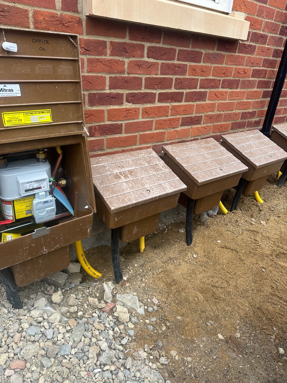 Row of gas meters and semi-concealed meter boxes at the new-build apartment block