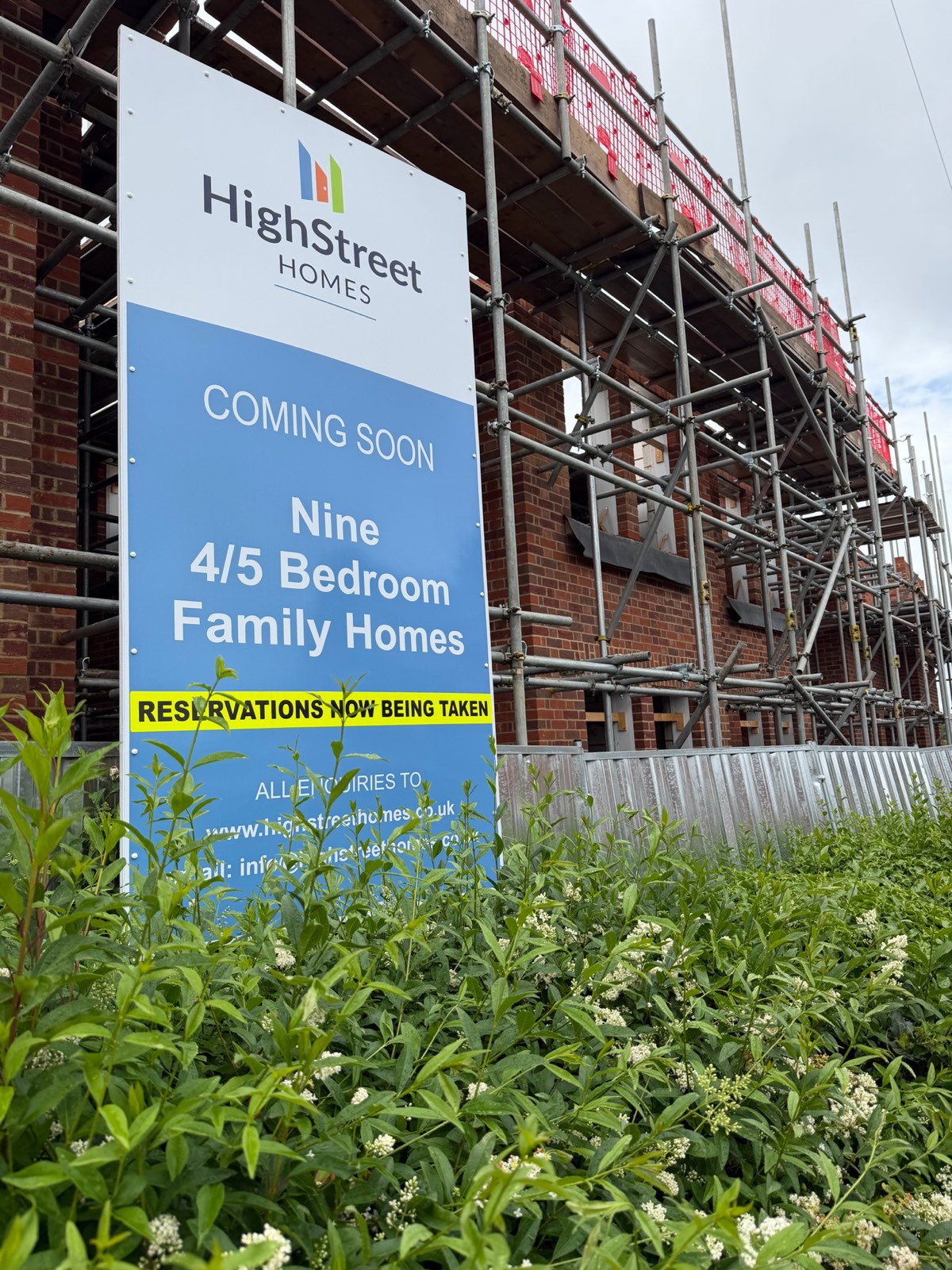 Site hoarding advertising reservations for nine new-build family homes in Bedford