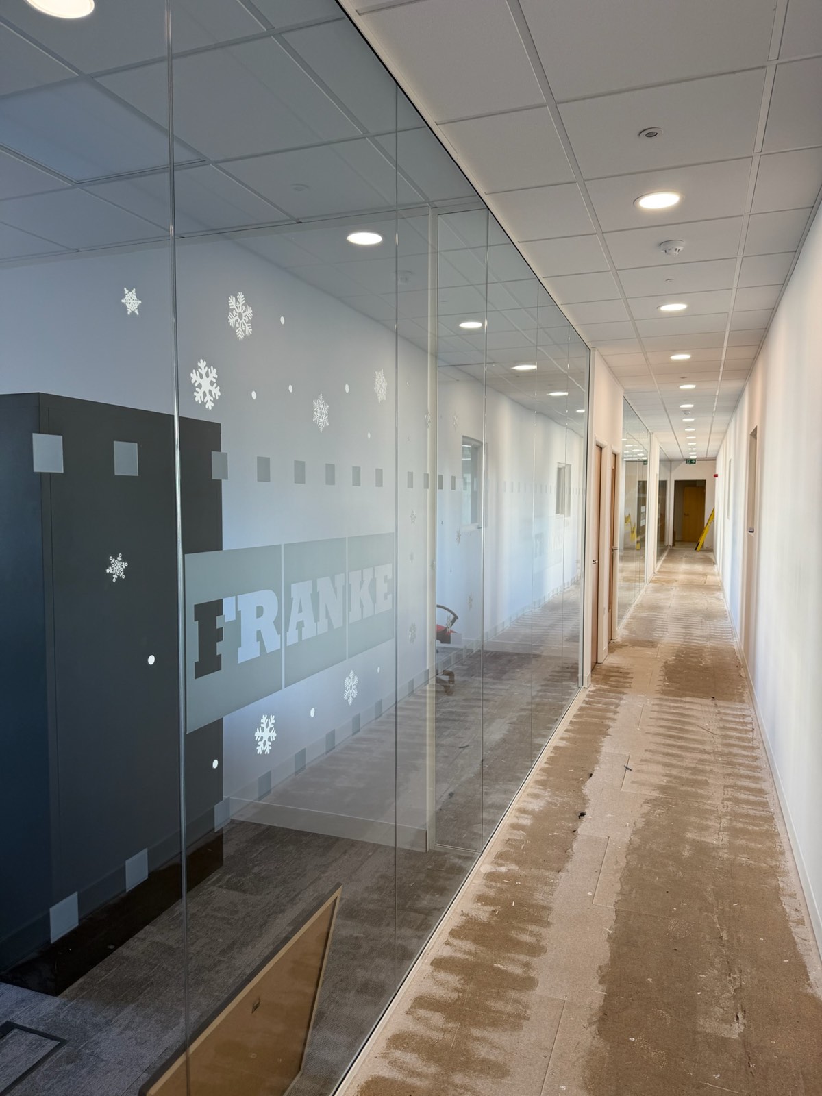 Finished office corridor with new suspended ceiling, recessed lighting and glazed partitions