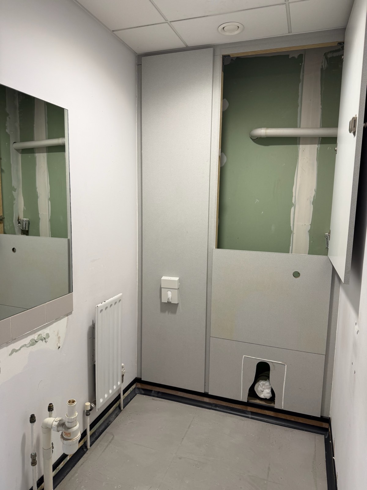 New commercial washroom with concealed WC, wall-hung basin and tiled splashback