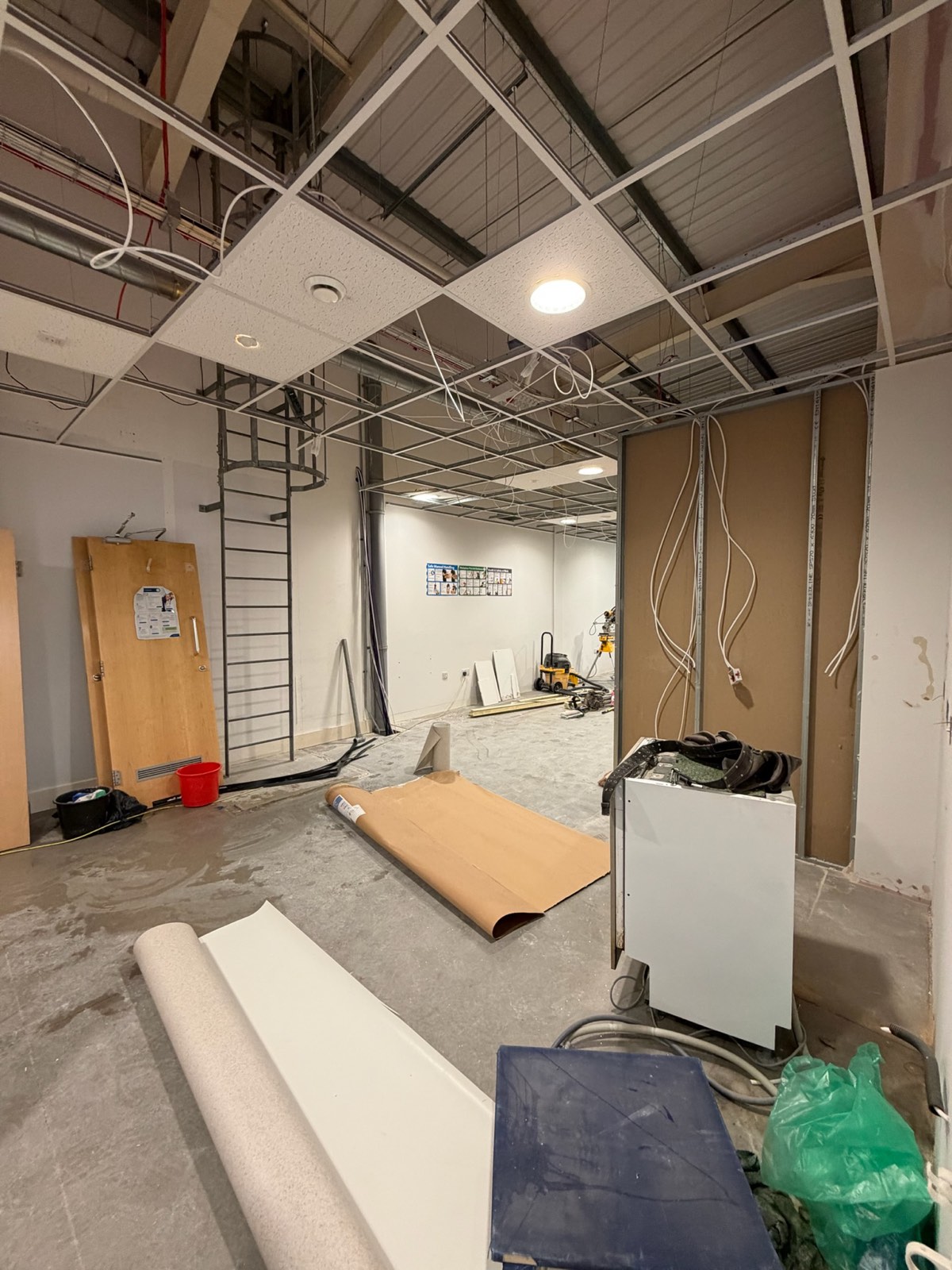 Office fit-out in progress with new ceiling grid, first-fix wiring and floor screed