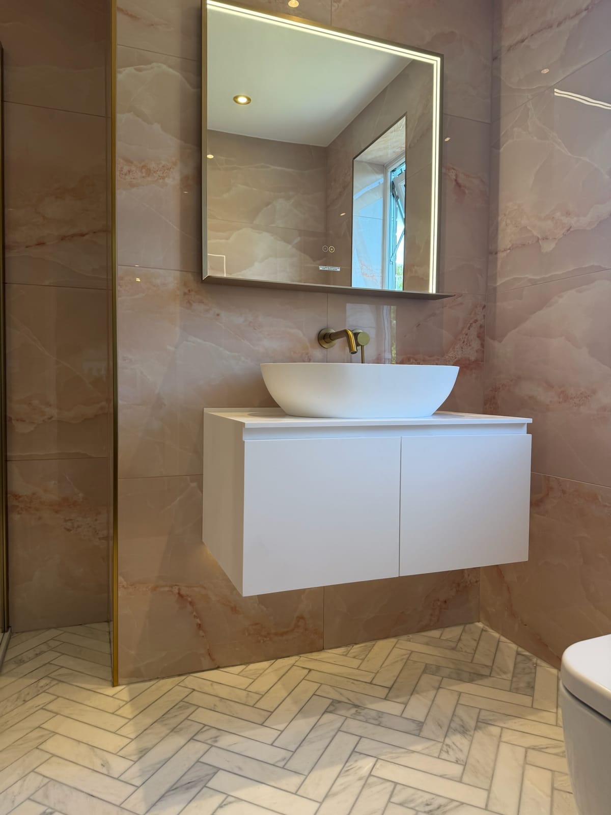 Counter-top basin and brushed brass mixer tap on a wall-hung vanity unit