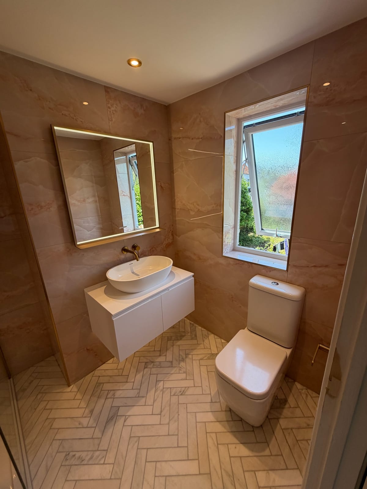Ensuite with wall-hung vanity unit, counter-top basin and backlit mirror