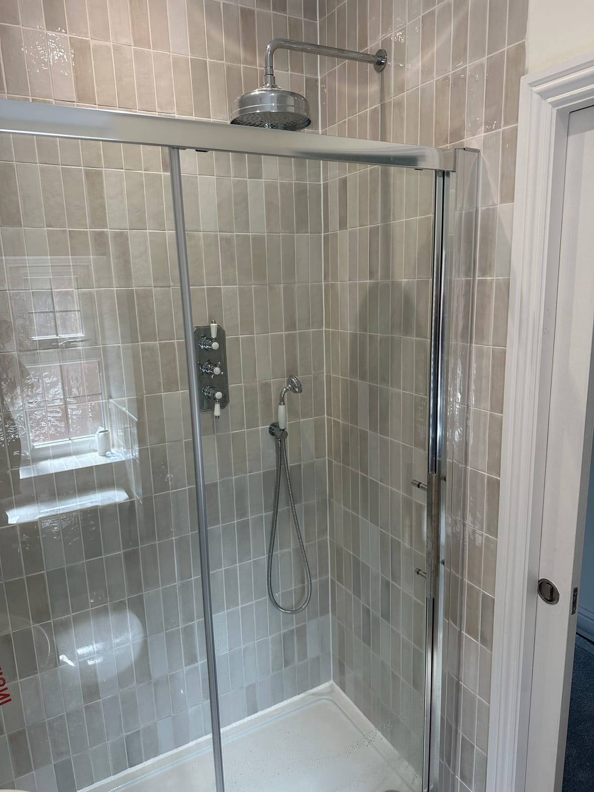 Sliding-door shower enclosure with an exposed thermostatic valve and rainfall head