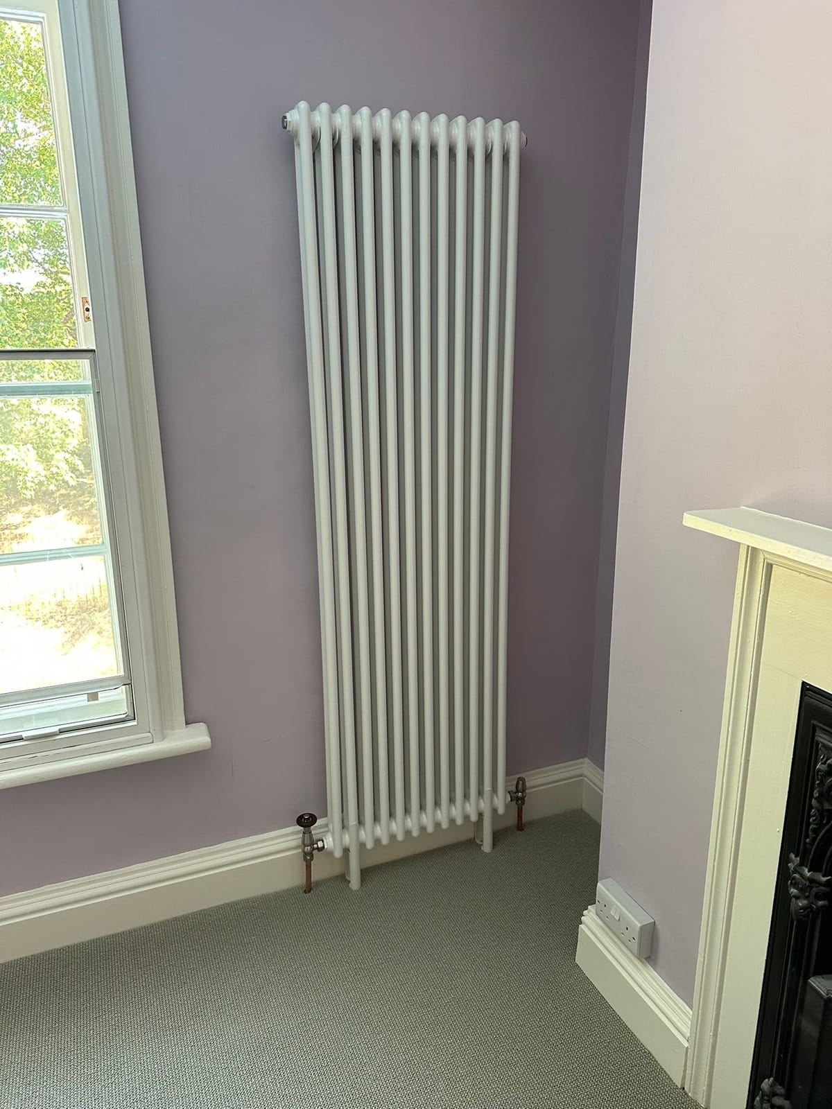 Vertical column radiator with a thermostatic valve, fitted in a period living room